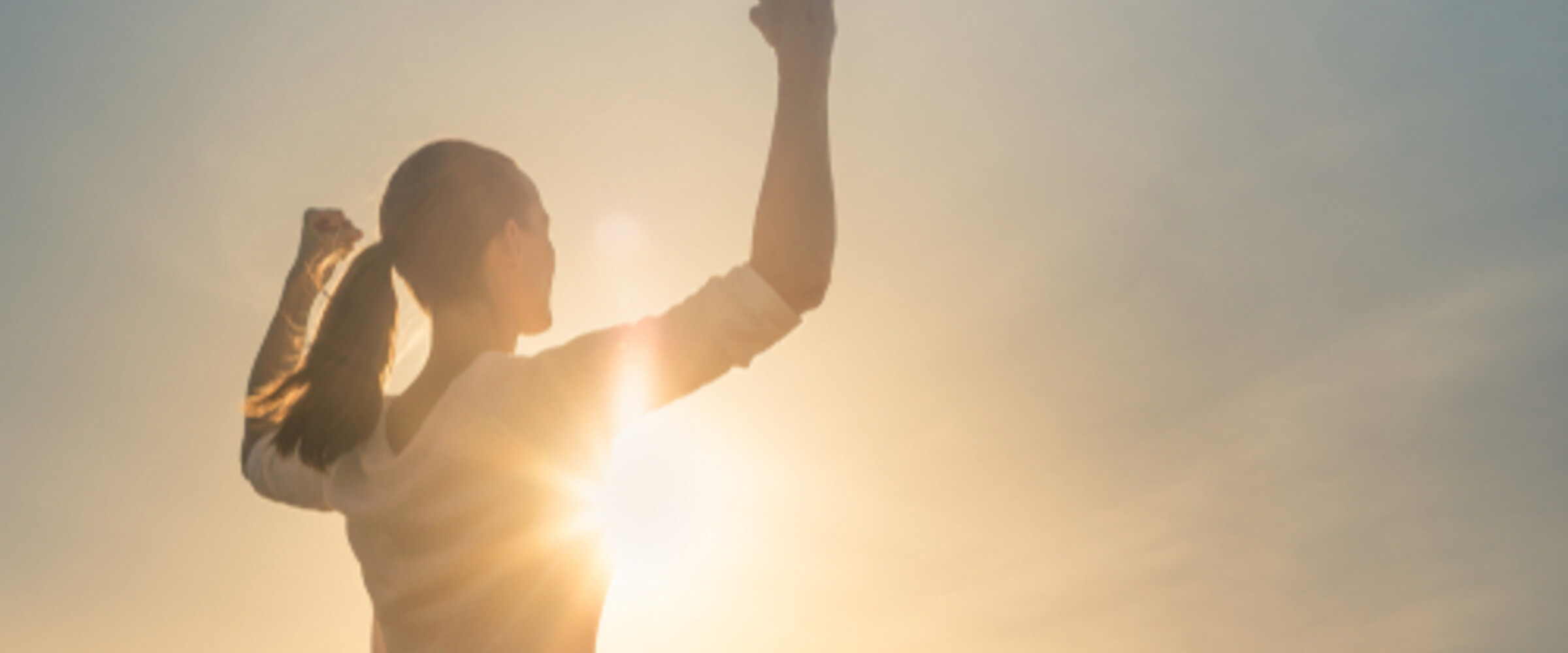 strong woman holding her arms up to the sun